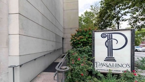Señal de Passalino's, un restaurante de ambiente clásico, situado en la esquina de un edificio con barandilla metálica y plantas.