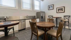 Una cocina moderna con comedor, que incluye una mesa redonda de madera, sillas, un refrigerador y un lavavajillas.