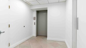 Un pasillo blanco y limpio con una puerta que da a un ascensor.