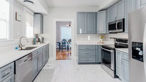 A modern kitchen with grey cabinets, stainless steel appliances, and a white countertop. - Park House - a Blackhouse Property (Tallahassee)
