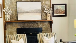 A living room with two striped armchairs, a fireplace, and framed artwork on the wall. - 3-Bdrm Home on Large Property at Norris Lake. Pet Friendly! (New Tazewell)
