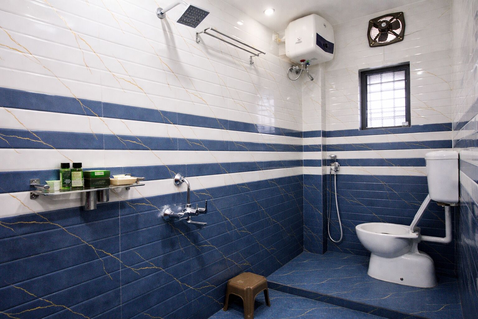 Un baño con ducha, inodoro y un taburete pequeño.