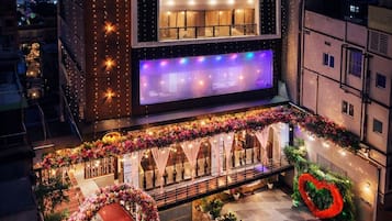 A modern building with a large illuminated display and a decorative entrance with floral arrangements.