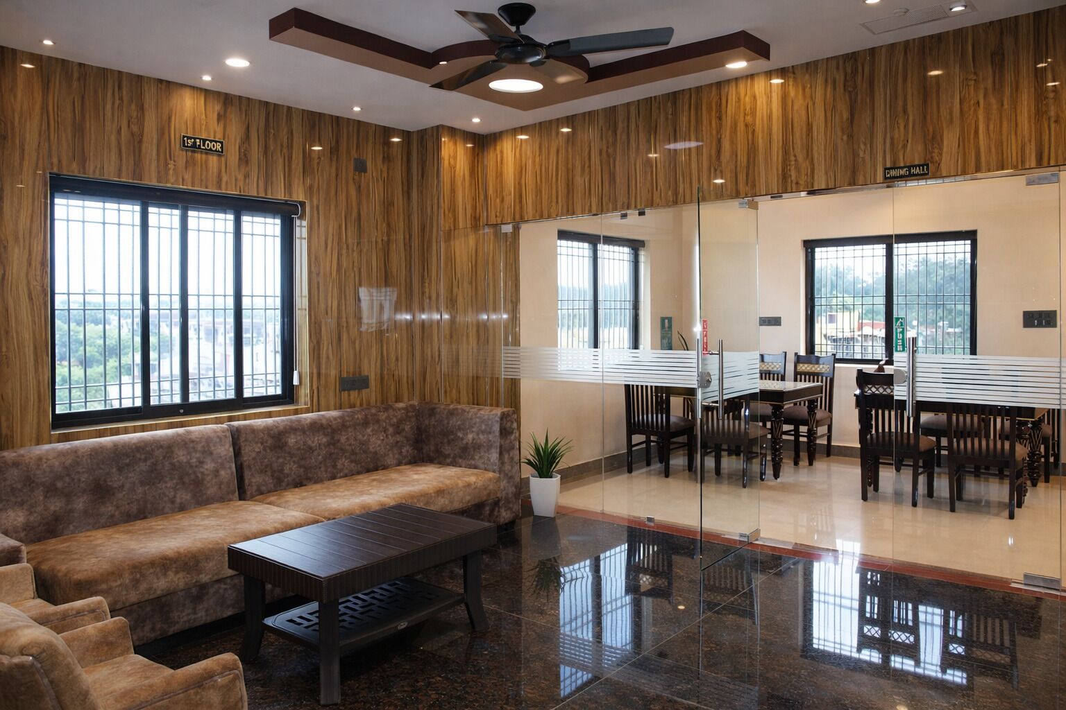 Un comedor moderno con techo alto, paneles de madera y un separador de vidrio.