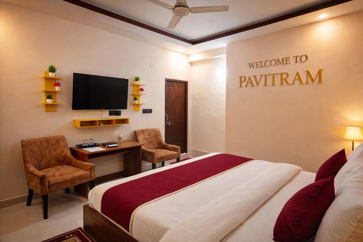 Una habitación de hotel con una cama, dos sillones, un escritorio con televisor de pantalla plana y una estantería con plantas.
