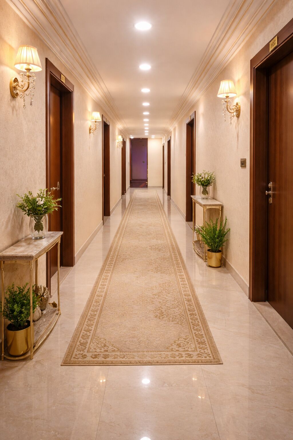 Un pasillo de hotel con suelo de mármol, puertas de madera y apliques en la pared.