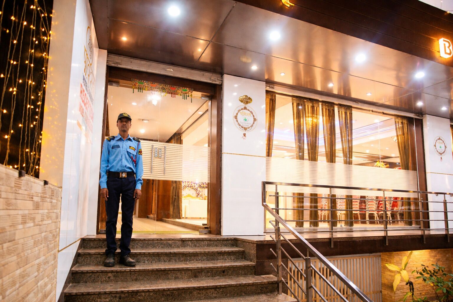 A hotel entrance with a security guard, a staircase, and a view of the interior.
