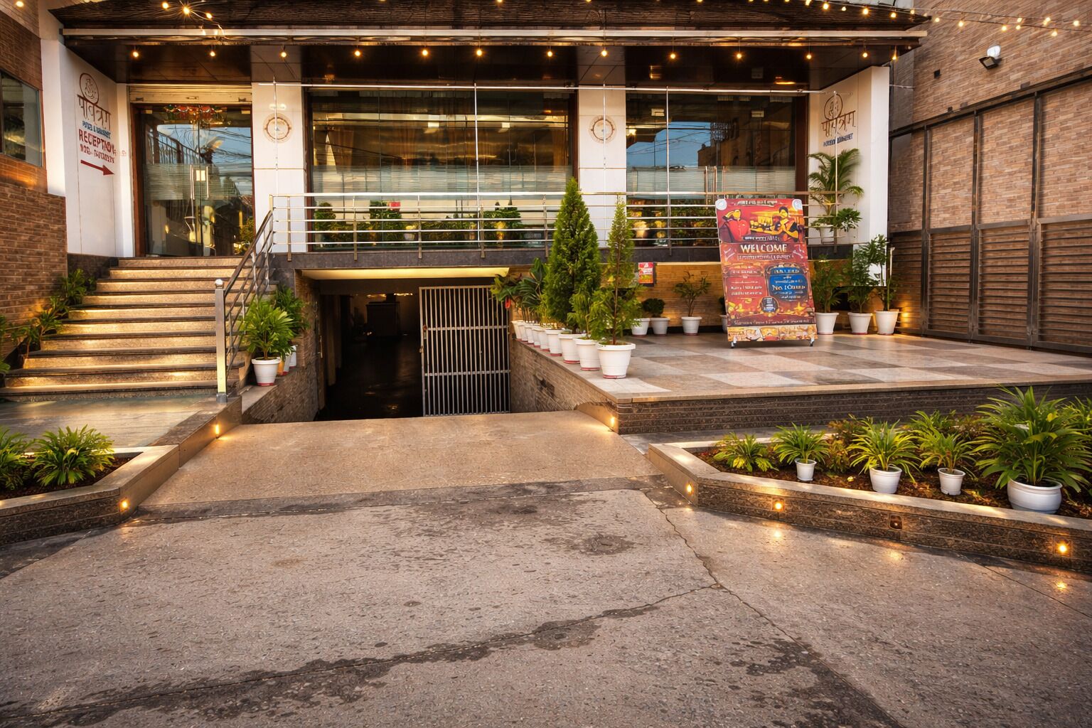 A building entrance with a staircase, potted plants, and a welcome sign.