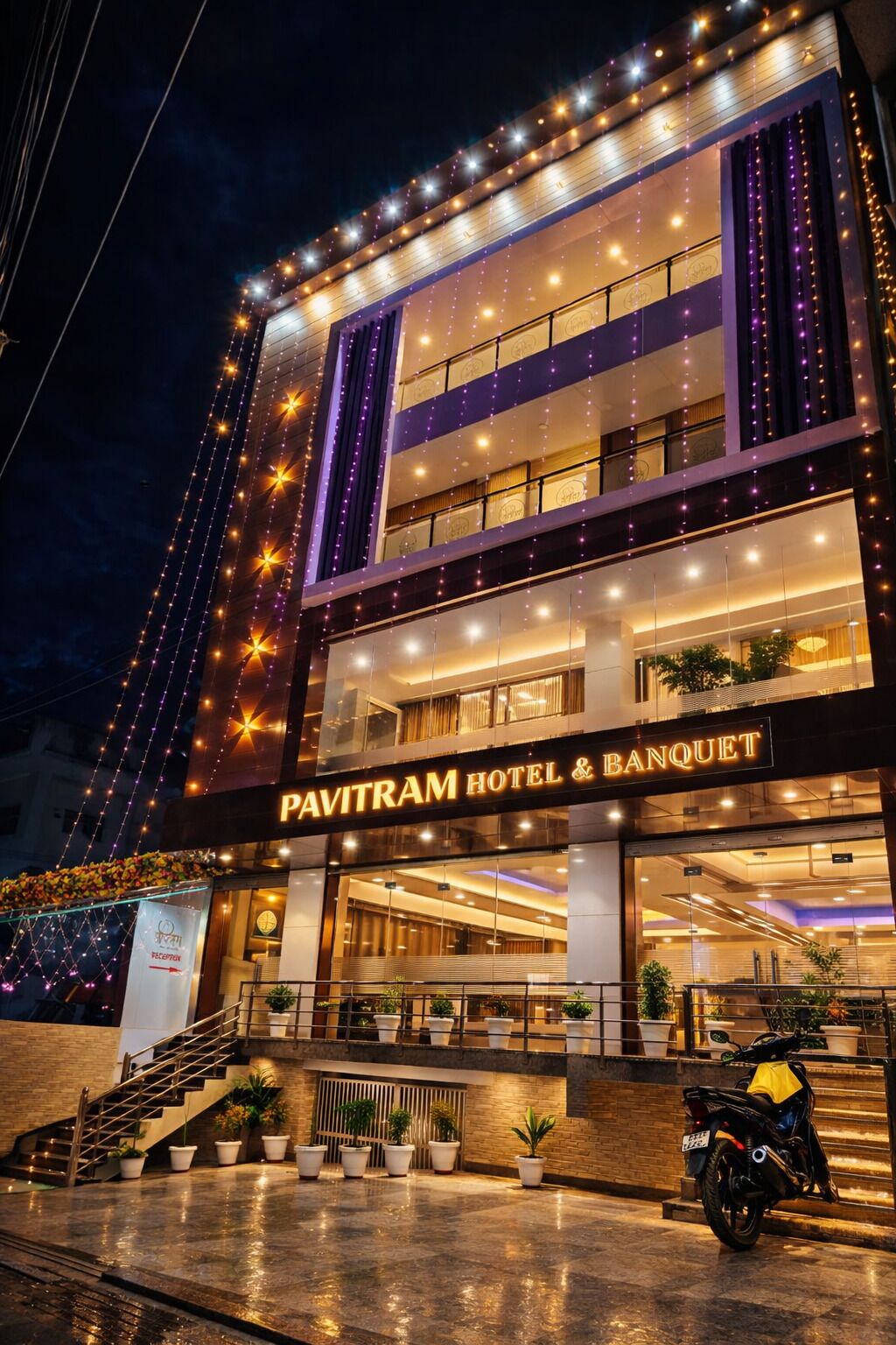 Pavitram Hotel & Banquet -hotellin moderni ulkoasu, jossa on useita kerroksia, sisäänkäyntiin johtavat portaat ja koristeelliset valonauhat.