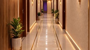 A long, well-lit hallway with doors on both sides, potted plants, and a polished floor. - Pavitram Hotel & Banquet (Ranchi)
