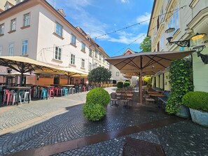 An outdoor café area with tables and chairs, surrounded by cobblestone pavement and buildings. - Studio Sviti Ljubljana Apartment Tour As by Town Hall (Ljubljana)