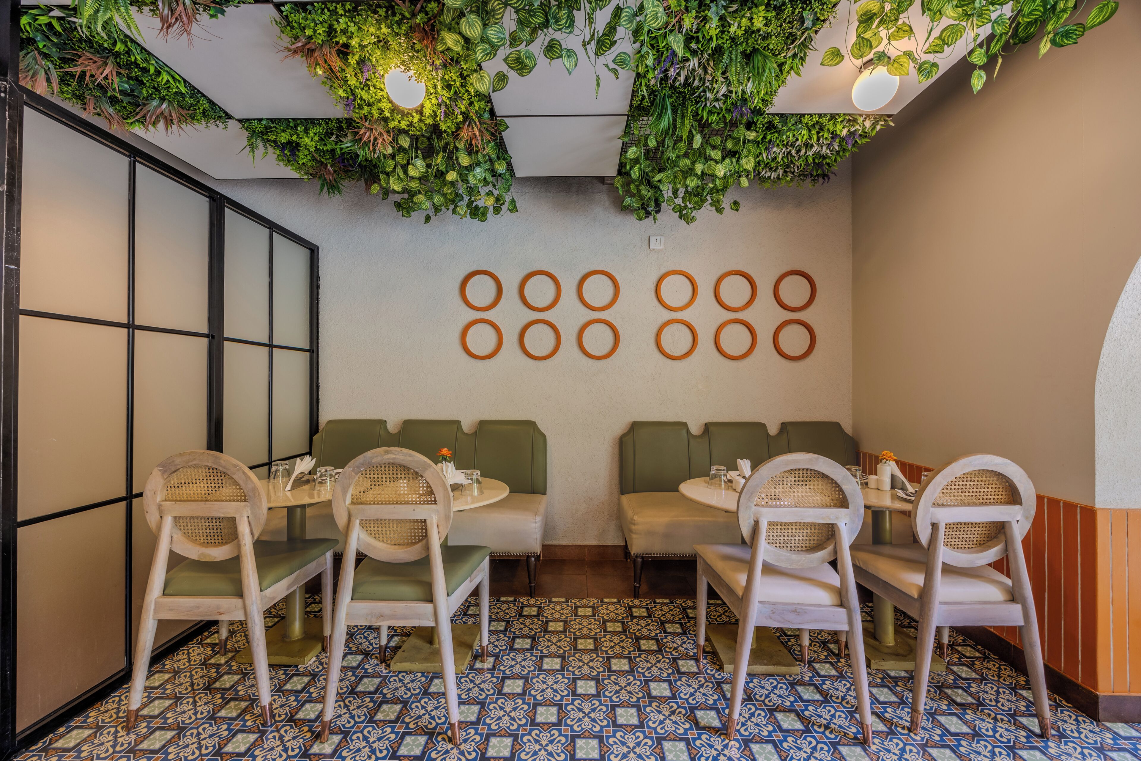 A restaurant with round tables, green cushioned booths, and a patterned tile floor.