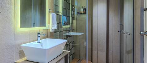 A modern bathroom with a glass-enclosed shower, a white sink, and a large mirror.