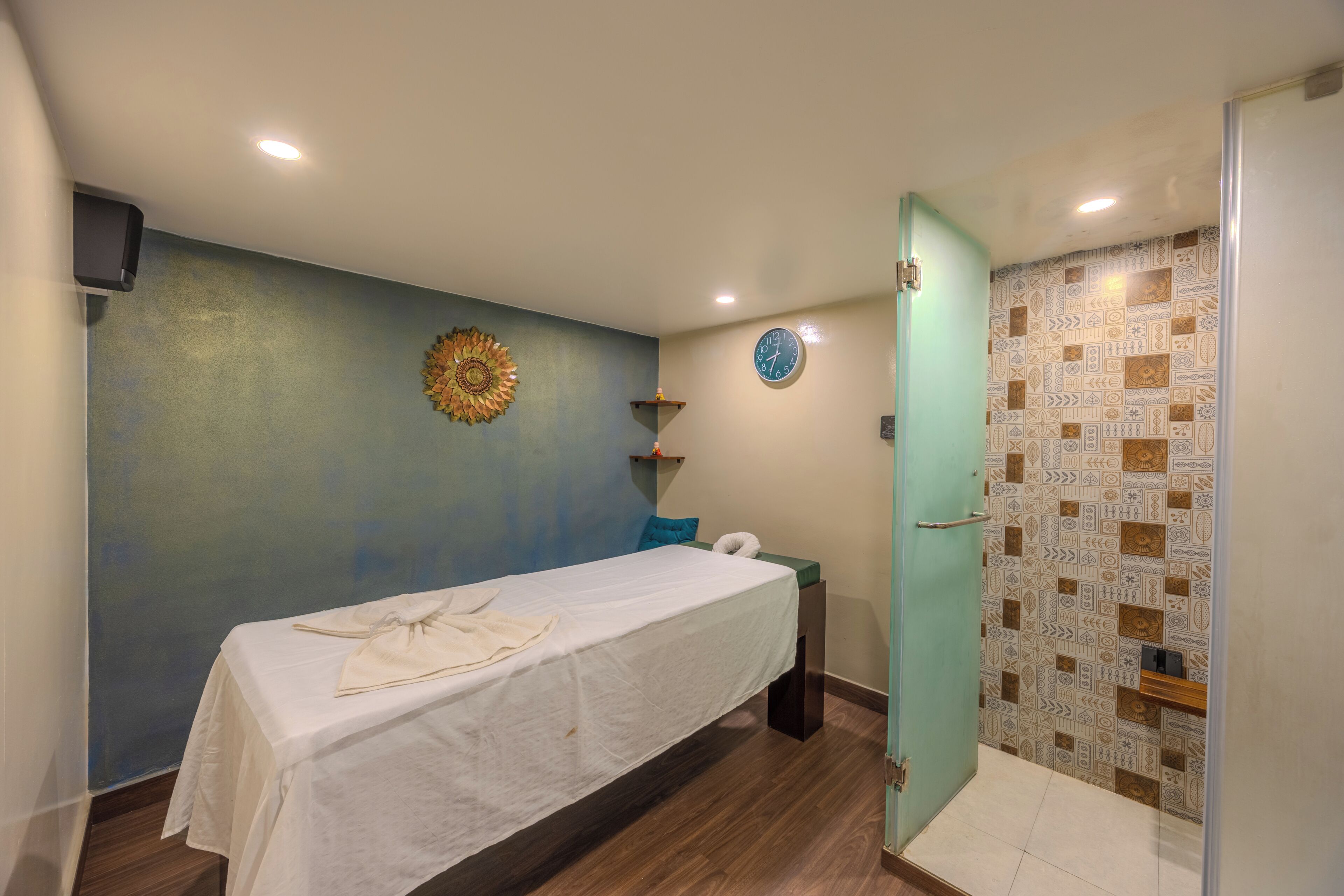 A room with a bed, a wall clock, a decorative sunburst, and a shower area.