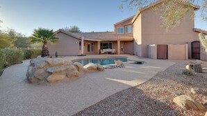 Una casa con piscina, un patio con mesa y sillas, y un jardín de cactus.