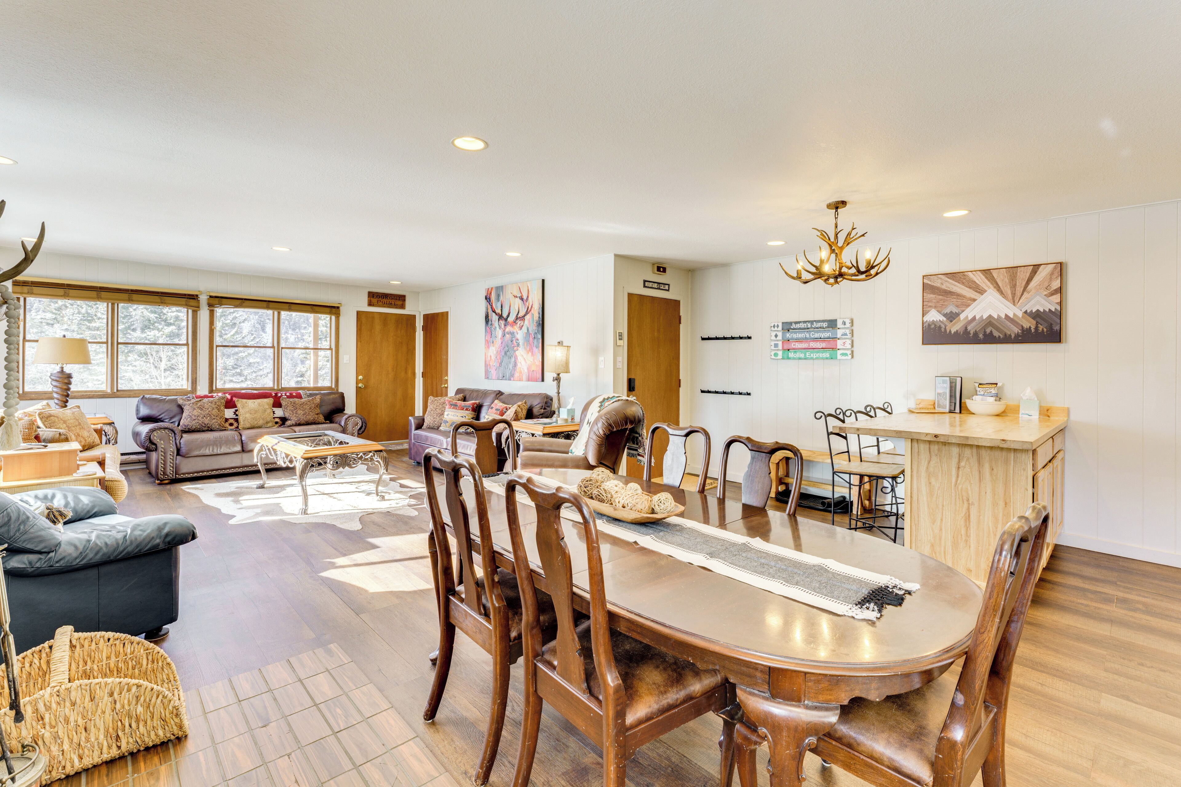 A spacious living area with a large wooden dining table, comfortable seating, and a kitchen area with a wooden countertop.