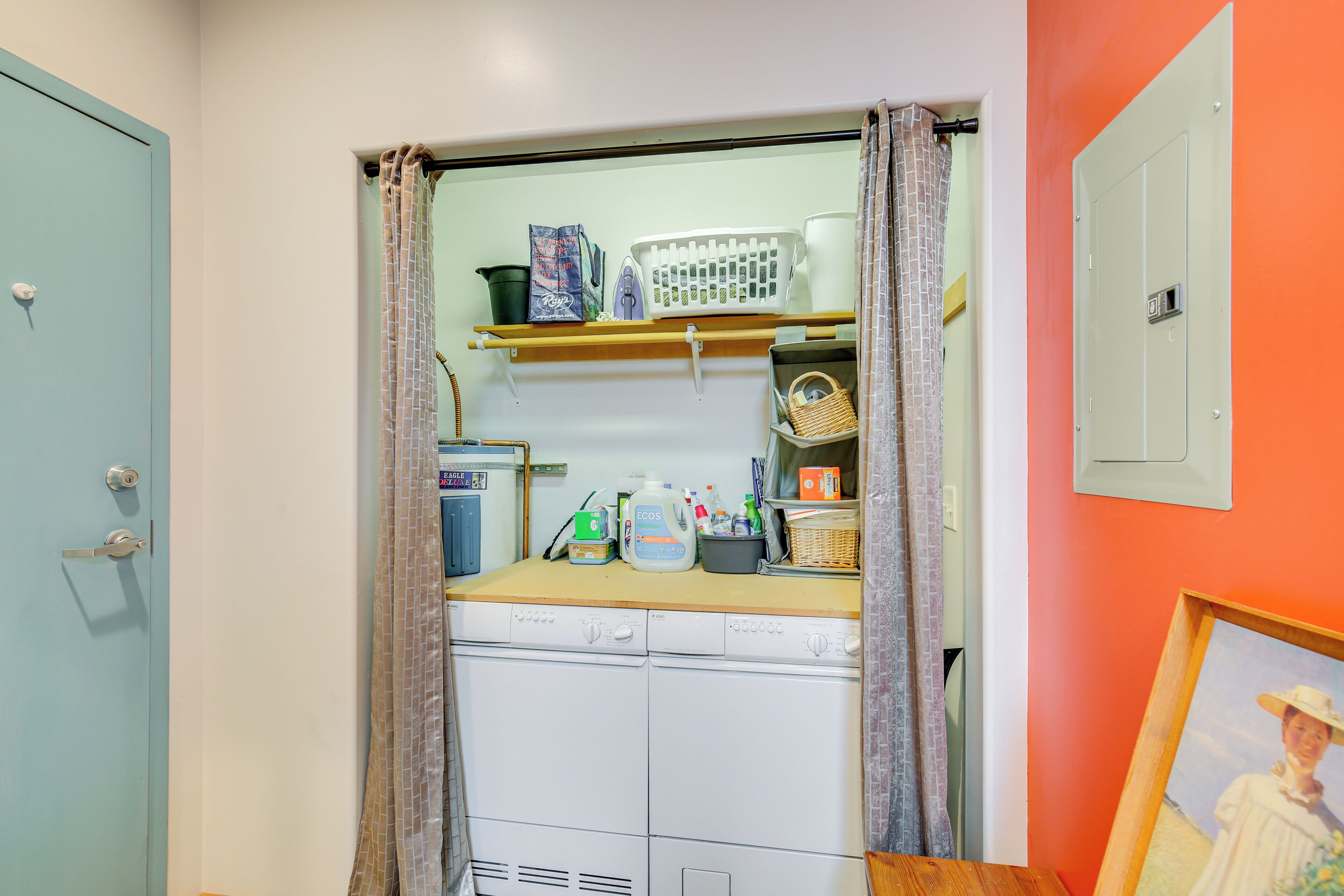 A laundry room with a washing machine, a drying rack, and various cleaning supplies.