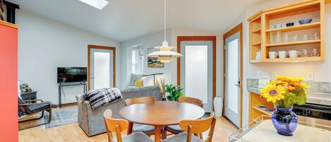 A modern kitchen with a dining area, wooden cabinets, and a vase with flowers.