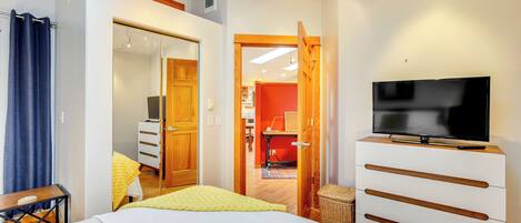 A hotel room with a bed, a TV, a wardrobe, and a bathroom visible through an open door.