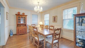 Comedor con mesa y sillas de madera, una araña y un aparador con puertas de vidrio.
