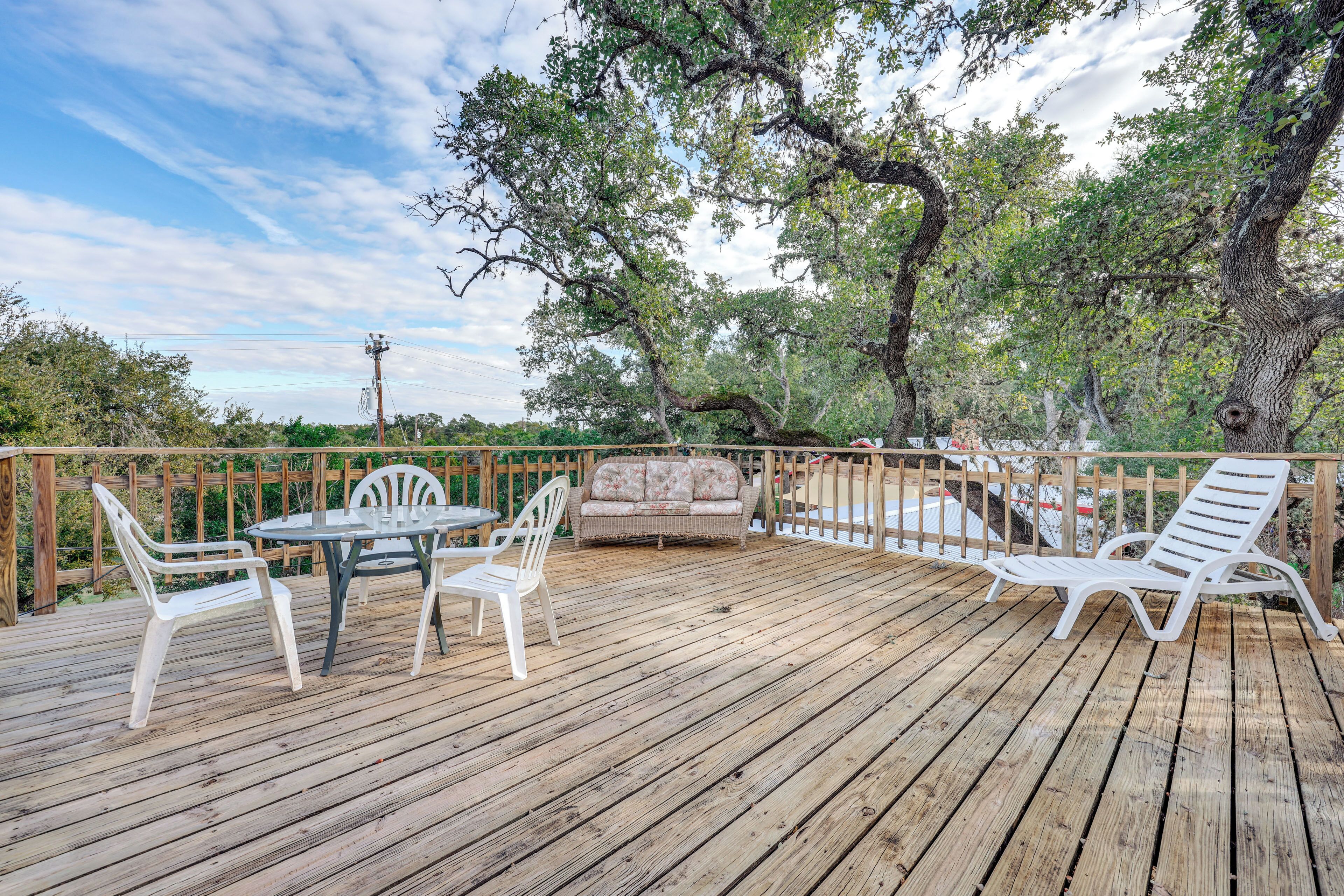A wooden deck with outdoor furniture, including a table and chairs, and a sofa.