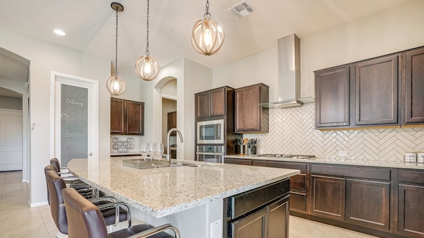 A modern kitchen with a large island, dark wooden cabinets, stainless steel appliances, and pendant lighting. - Covered Patio & Community Pool: Home in Surprise (Surprise)