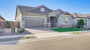 A single-story house with a garage, a front lawn, and a small garden area. - Covered Patio & Community Pool: Home in Surprise (Surprise)