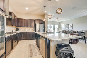 A modern kitchen with dark wood cabinets, stainless steel appliances, and a large island.