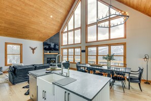Una cocina amplia con una isla central, ventanas grandes y un techo alto.