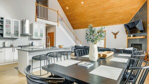 Una cocina amplia con una isla central, armarios blancos y una escalera de madera.