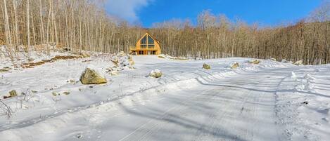 Paisaje nevado con una cabaña de madera grande al fondo.