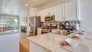 A modern kitchen with white cabinets, stainless steel appliances, and a granite countertop. - Avondale Home w/ Heated Pool & Putting Green! (Avondale)