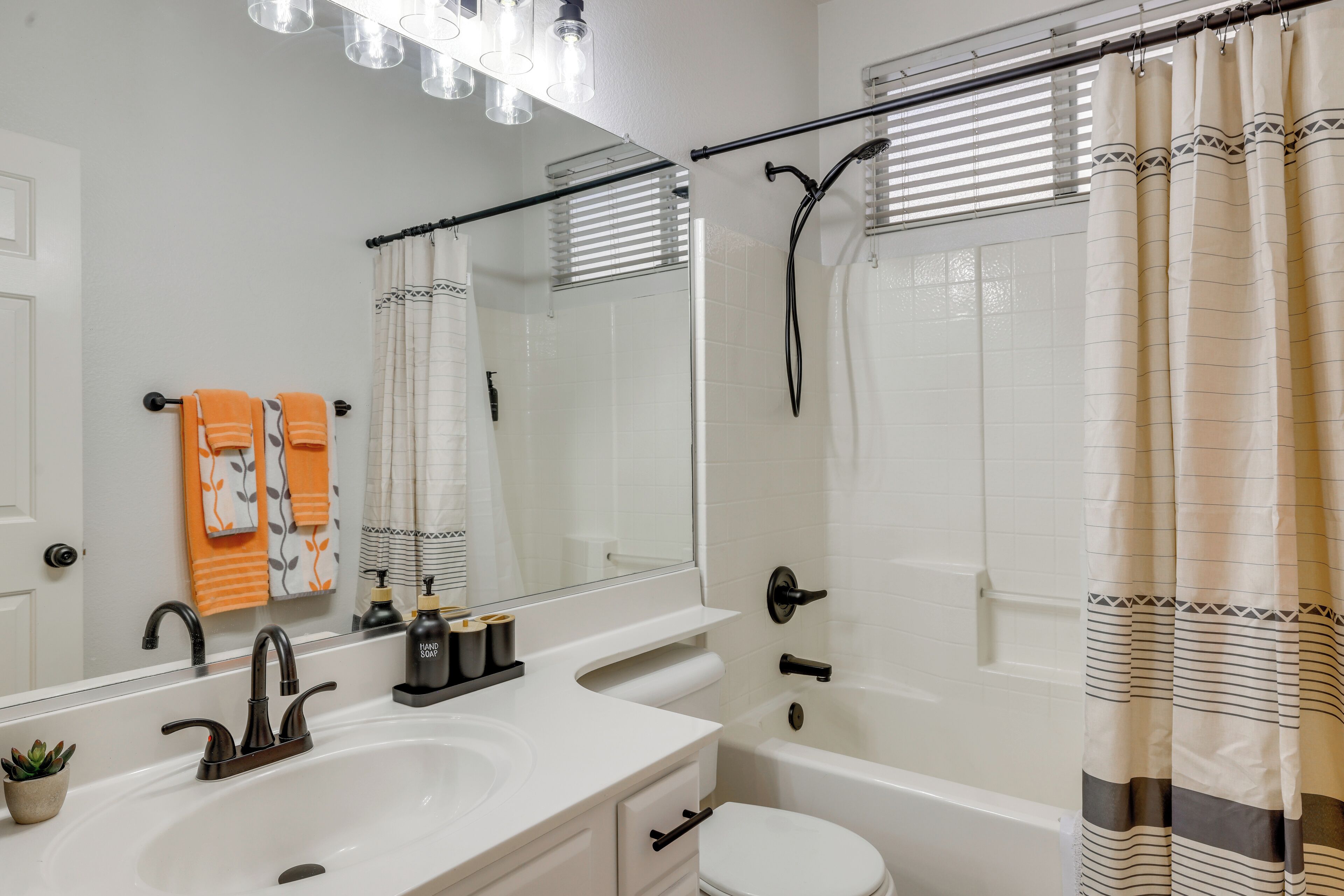 A bathroom with a white sink, black faucet, and a bathtub with a shower curtain.