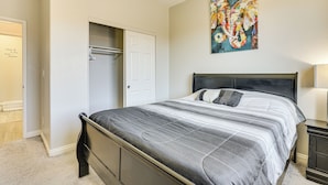A bedroom with a bed, a door, a closet, and a painting on the wall. - 1 Mi to Aliante Casino: Townhome w/ Fenced Yard! (North Las Vegas)