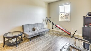 A living room with a gray sofa, a small round table, a treadmill, and a bookshelf. - 1 Mi to Aliante Casino: Townhome w/ Fenced Yard! (North Las Vegas)