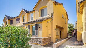 A yellow two-story house with a tiled roof, a satellite dish, and a small front yard with shrubs. - 1 Mi to Aliante Casino: Townhome w/ Fenced Yard! (North Las Vegas)