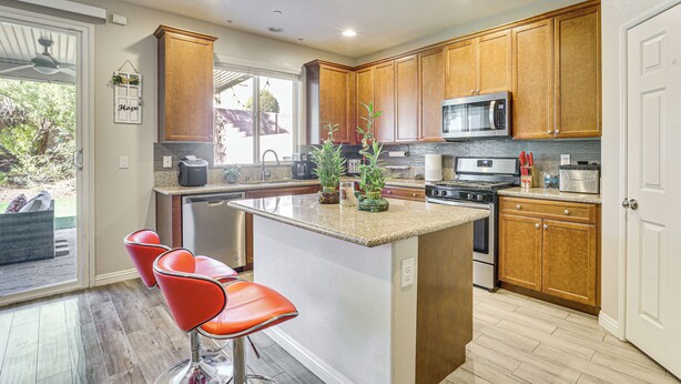 A modern kitchen with wooden cabinets, a central island, and a microwave. - 1 Mi to Aliante Casino: Townhome w/ Fenced Yard! (North Las Vegas)
