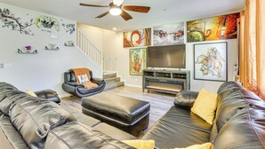 A modern living room with a black leather sofa, a fireplace, and a ceiling fan. - 1 Mi to Aliante Casino: Townhome w/ Fenced Yard! (North Las Vegas)