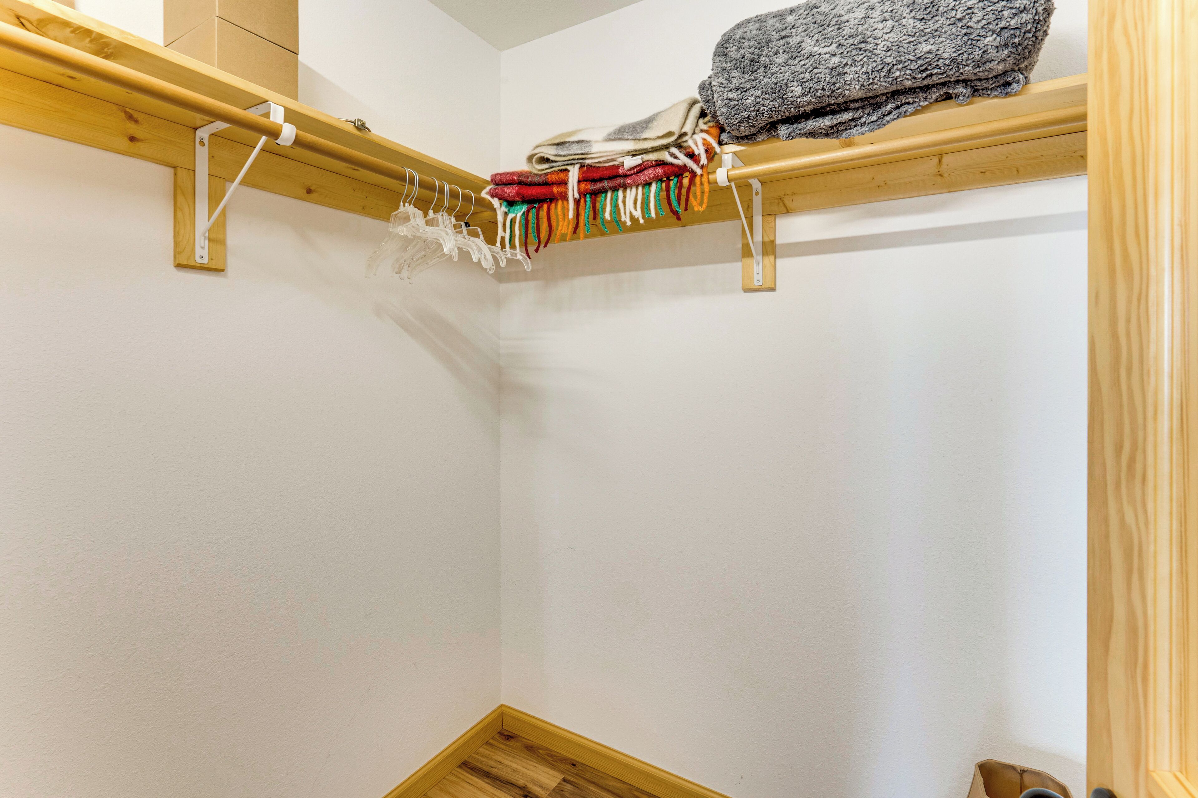 Un coin de pièce avec un plafond en bois apparent, un mur blanc et un plancher en bois.