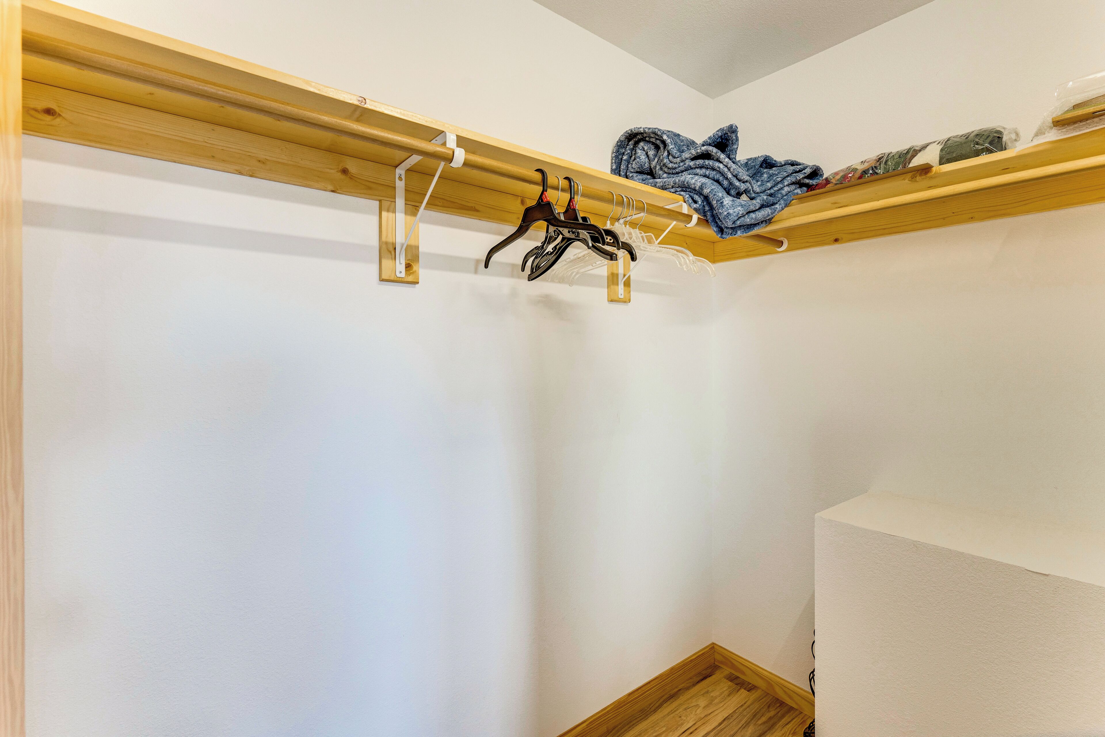 Un rincón de habitación con techo de vigas de madera, pared blanca y suelo de madera.
