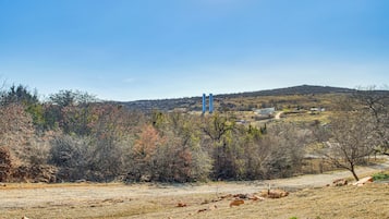 Paisaje rural con cielo despejado, un camino de tierra y una estructura azul a lo lejos.