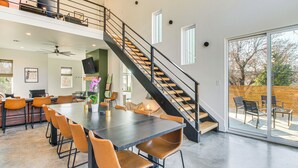 Un comedor amplio con una mesa grande y sillas, una escalera con barandilla y un amplio ventanal corredero que da a un patio exterior.