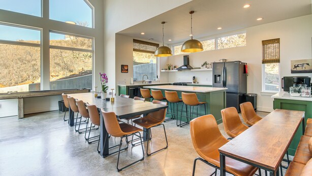 Una cocina moderna con ventanas amplias, un comedor con sillas y una isla central.