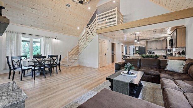 A spacious living area with a wooden staircase, a dining set, and a kitchen in the background. - 10-acre Property w/ Fire Pit & Grill in Arkdale! (Arkdale)