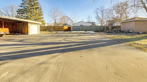 Une allée menant à une propriété résidentielle, avec un garage, une clôture en bois et un garage séparé.