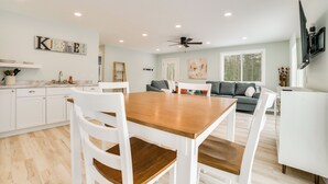 A modern kitchen with white cabinetry, a wooden dining table, and a gray sofa in the living area. - 3 Mi to Lake Huron: Secluded Home in Rogers City (Rogers City)