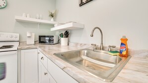 A modern kitchen with a stainless steel sink, white cabinets, a microwave, and a white stove. - 3 Mi to Lake Huron: Secluded Home in Rogers City (Rogers City)