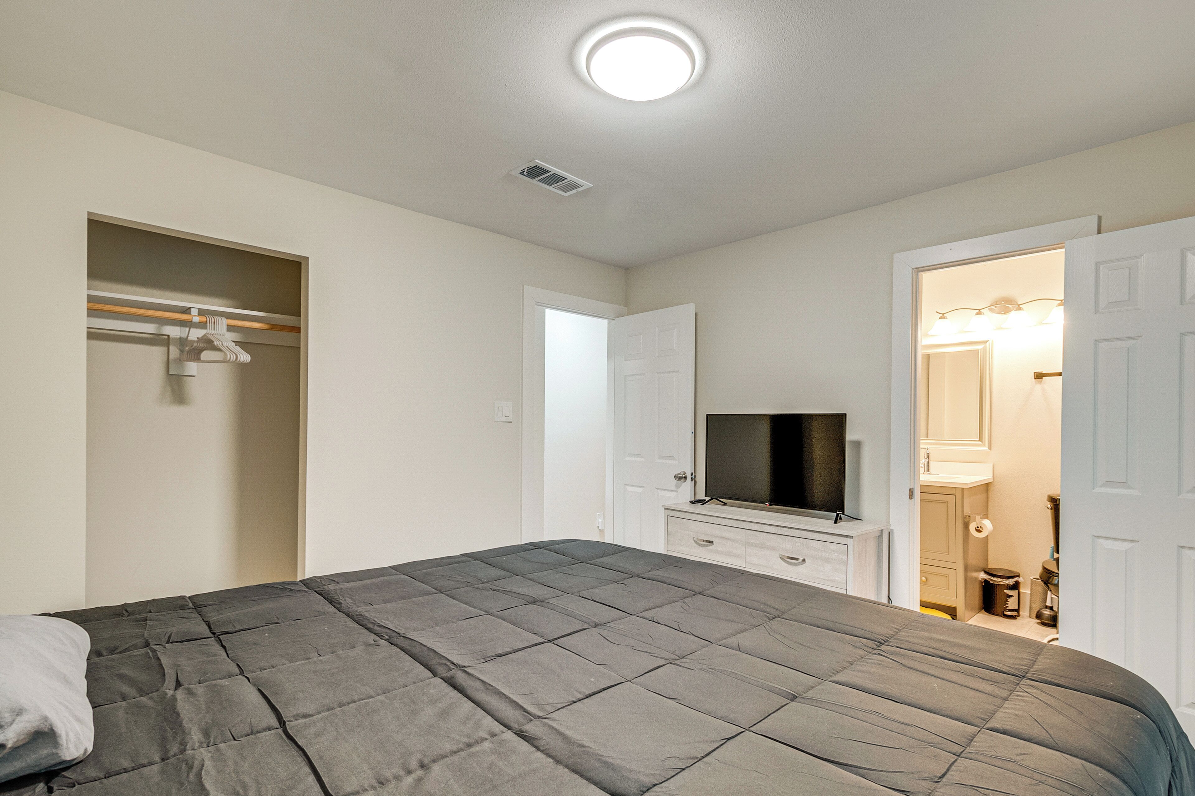 Een slaapkamer met een bed, een televisie, een kledingkast en een open deur naar een badkamer.