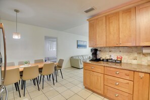 A modern kitchen with wooden cabinets, a coffee bar, and a dining area with a table and chairs. - 4 Mi to Shore: Family Home in Daytona Beach (Holly Hill)