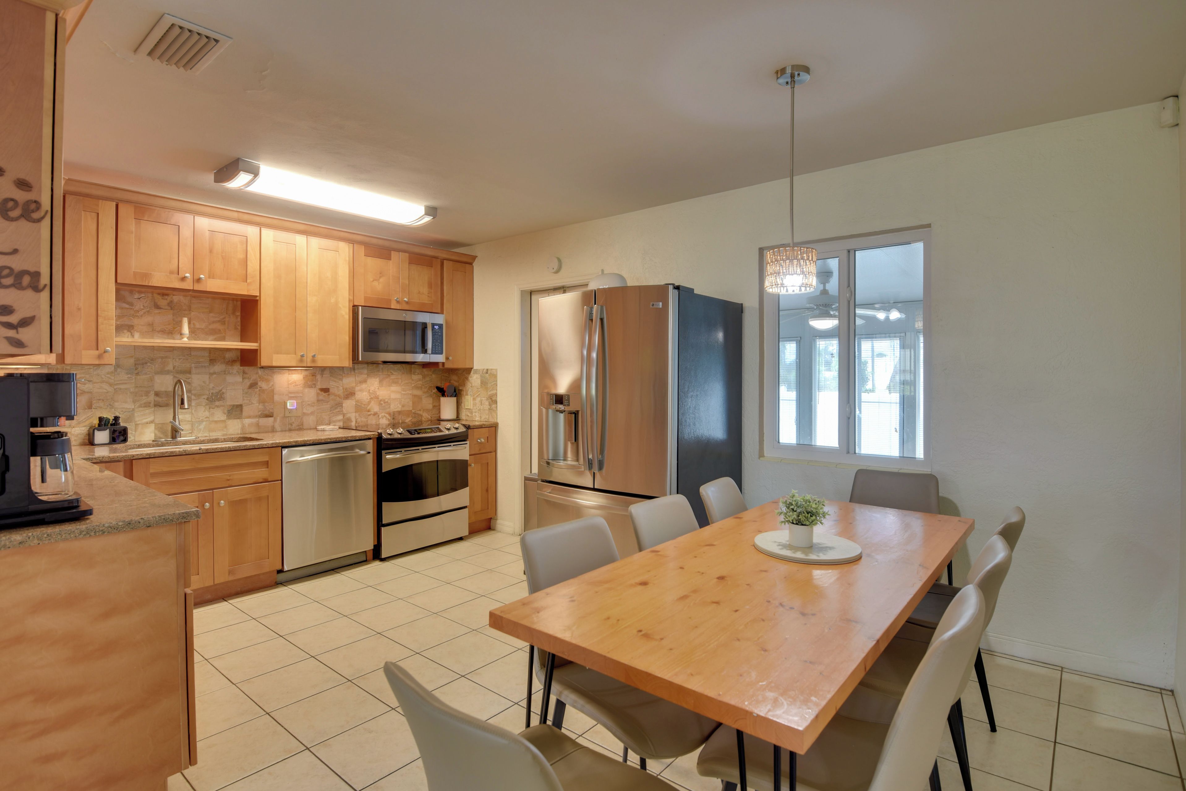 Una cocina moderna con armarios de madera, electrodomésticos de acero inoxidable y un comedor con mesa y sillas de madera.